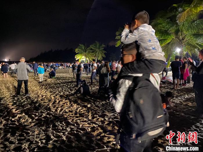 一位兒童坐著父親的肩上用望遠(yuǎn)鏡觀(guān)看文昌航天發(fā)射場(chǎng)。凌楠 攝