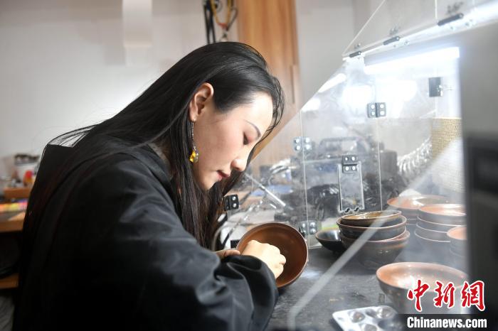 在唐潔工坊內(nèi)，“90后”文物修復(fù)師瞿汕正低頭忙碌。　呂明 攝