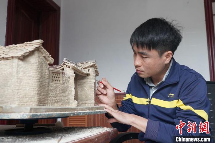 圖為黃簡松在細致雕琢民居細節(jié) 蒲文思 攝